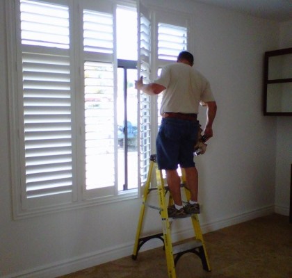 A man on a ladder painting the window.