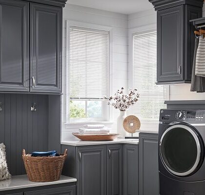 Modern laundry room with gray cabinetry and natural light.