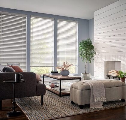 Gray Venetian blinds by fireplace and ottoman