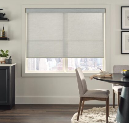 A cozy dining area with a window covered by light gray roller shades.